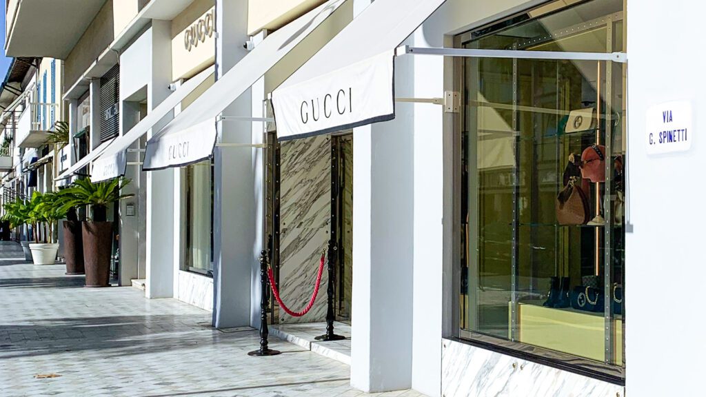 Forte dei Marmi, oltre l’estate: vivere la Versilia come un vero local 1 Facciata del negozio Gucci in una via elegante con marciapiede in marmo e vasi con piante, in una giornata soleggiata a Forte dei Marmi.