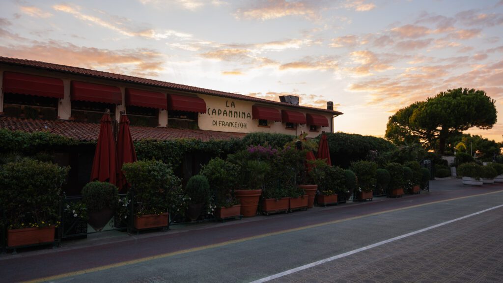 Forte dei Marmi, oltre l’estate: vivere la Versilia come un vero local 2 Facciata del locale La Capannina di Franceschi a Forte dei Marmi al tramonto, con cielo colorato e vegetazione rigogliosa lungo la strada.