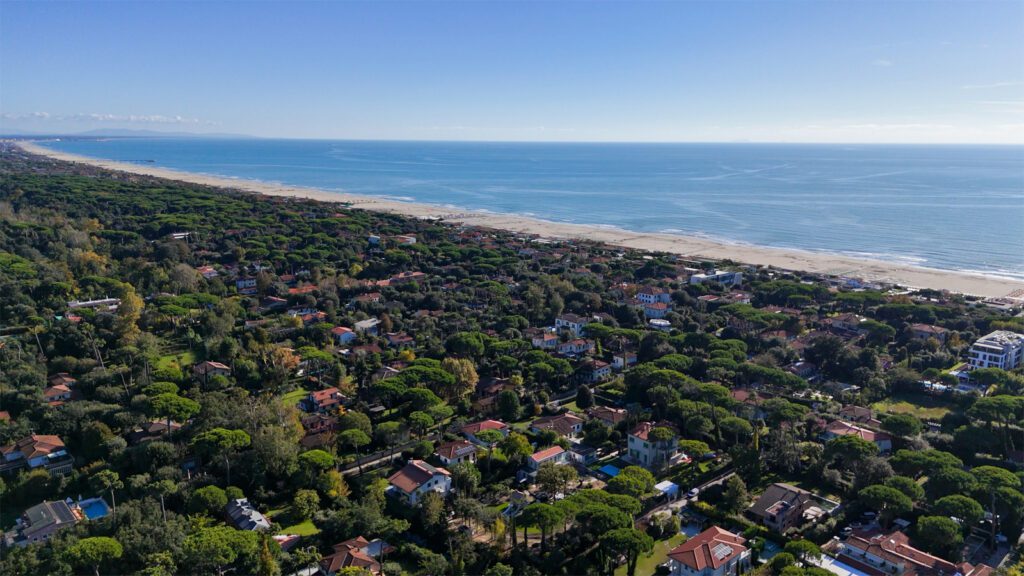 Investire in una villa a Forte dei Marmi: lusso senza tempo e nuove opportunità 2 Veduta aerea di Forte dei Marmi con le ville immerse nel verde e la lunga spiaggia sabbiosa affacciata sul Mar Tirreno in una giornata limpida.
