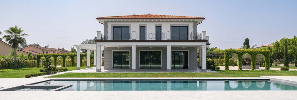 Villa moderna con piscina e giardino curato a Forte dei Marmi, vista frontale della facciata principale con ampie vetrate e terrazza.