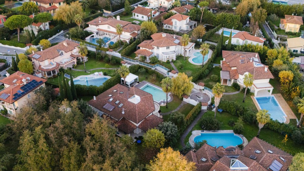 Vista aerea di un quartiere residenziale a Forte dei Marmi con ville di lusso e piscine immerse nel verde.