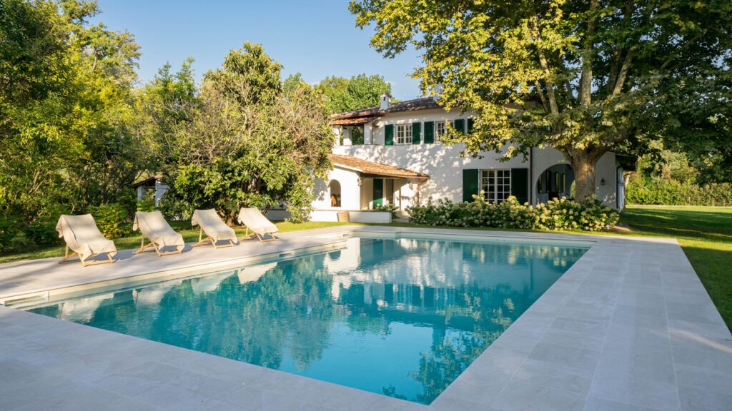 Villa in Versilia immersa nel verde con piscina privata, ampio giardino e architettura elegante, ideale per vivere il lifestyle esclusivo della costa toscana.