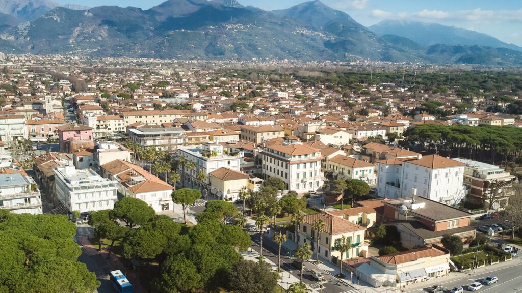 Vista panoramica di Forte dei Marmi con il centro abitato, le Alpi Apuane sullo sfondo e le tipiche case della Versilia